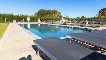 Une piscine avec des chaises longues et une terrasse en bois.