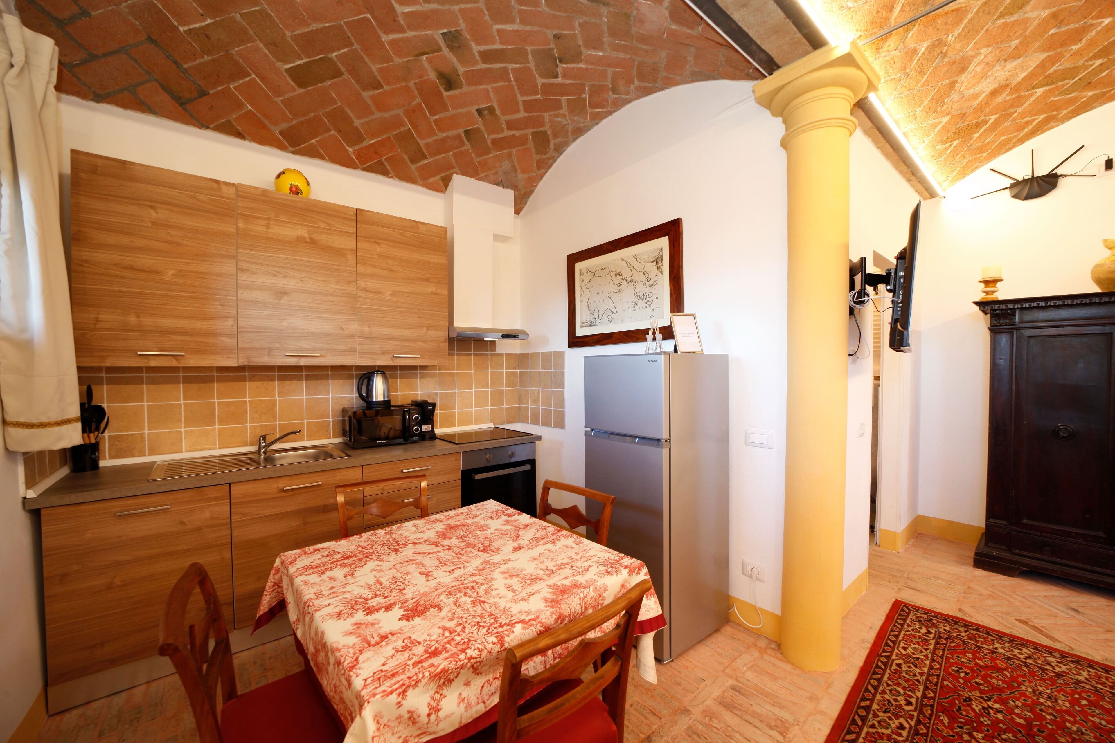 A compact kitchen with wooden cabinets, a sink, and a dining area with a table and chairs.