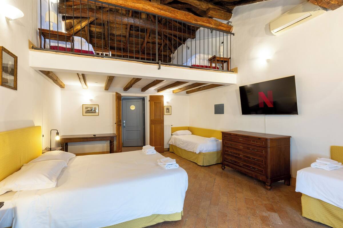 Une chambre d’hôtel avec deux lits, une télévision, une commode en bois et un balcon avec une balustrade.