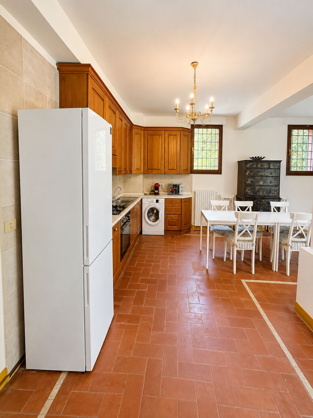 Une cuisine équipée d’un réfrigérateur, d’un lave-linge et d’une table à manger avec des chaises.