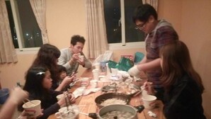A group of people around a wooden table with a large pot and various dishes, suggesting a communal meal setting. - No.160 7th St. B&B (Ji'an)