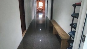 A narrow hallway with a bench, a shoe rack, and a door at the end. - No.160 7th St. B&B (Ji'an)