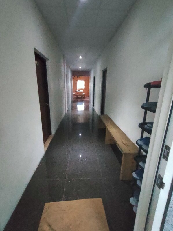 A narrow hallway with a bench, a shoe rack, and a door at the end.