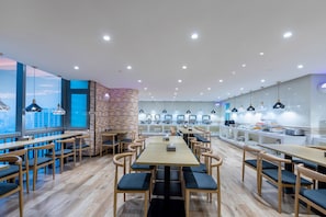 A modern restaurant with wooden tables and chairs, a brick accent wall, and a city view. - One&One Residence (Guangzhou)
