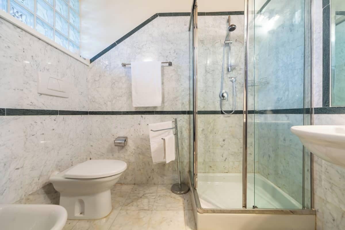 A bathroom with a toilet, a glass-enclosed shower, and a sink.