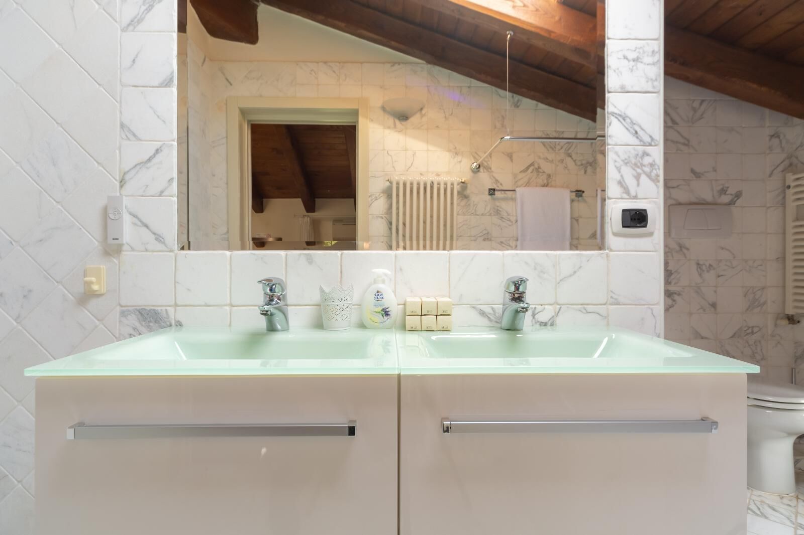 A bathroom with a glass sink, two faucets, a mirror, and a towel rack.