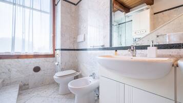 A bathroom with a marble floor, a white sink, a bidet, and a toilet.