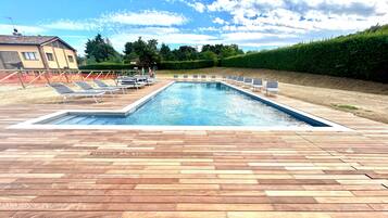 Una piscina rectangular con una terraza de madera al frente.