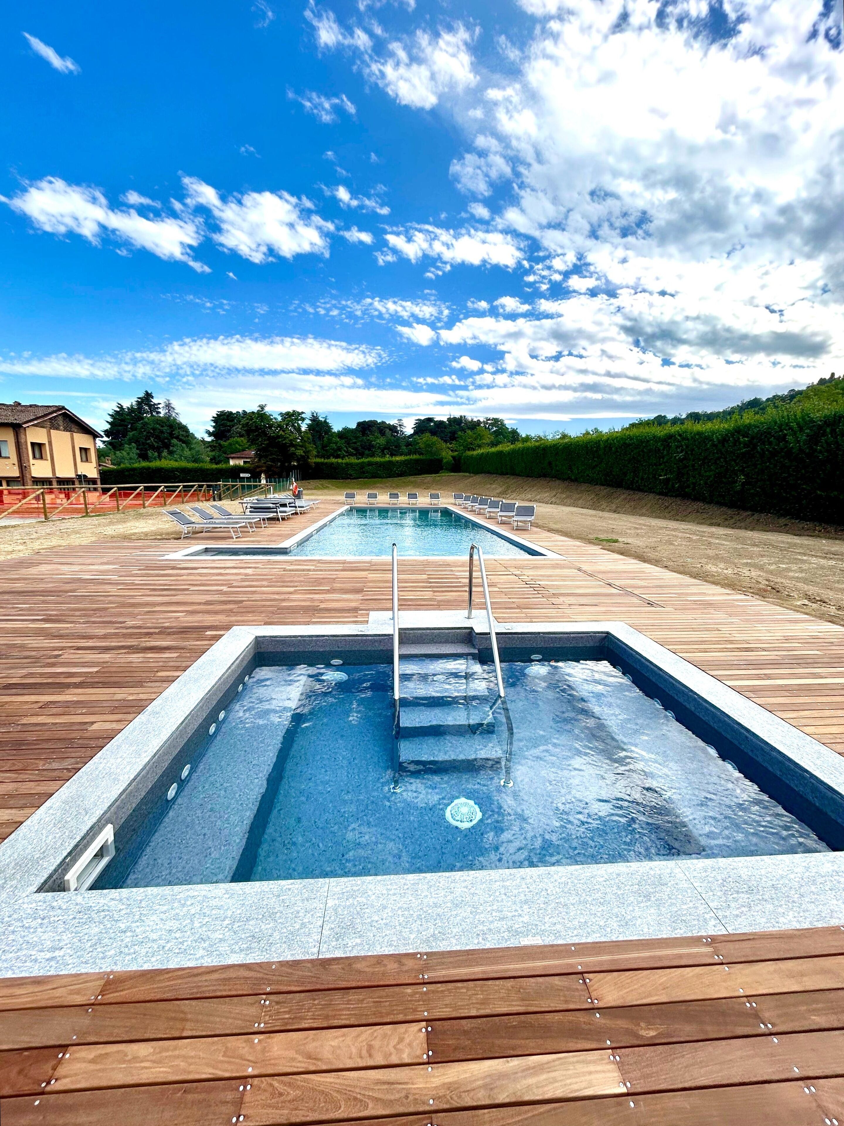 A swimming pool with a wooden deck, a ladder, and lounge chairs.
