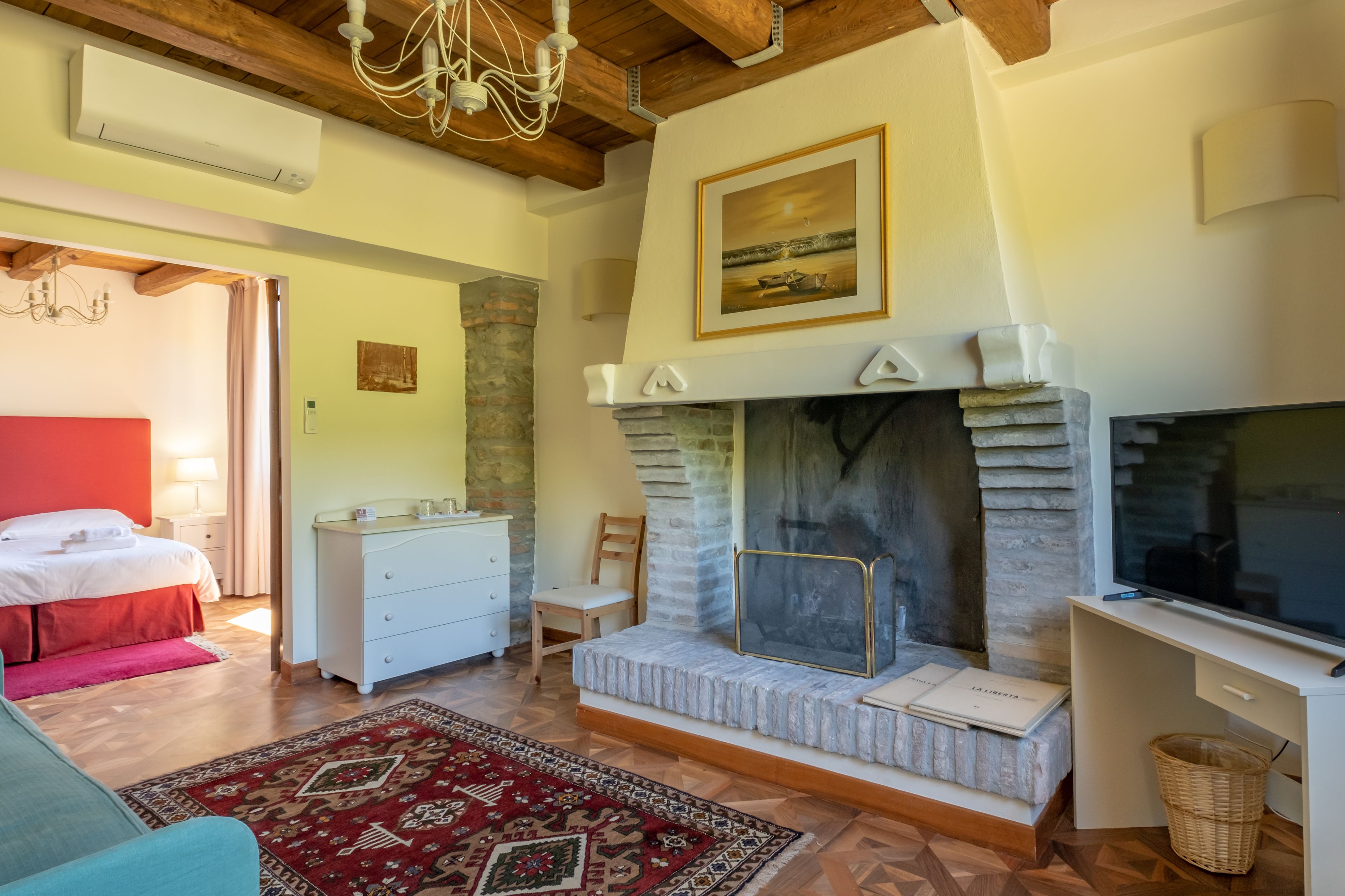 A bedroom with a bed, dresser, and a fireplace.