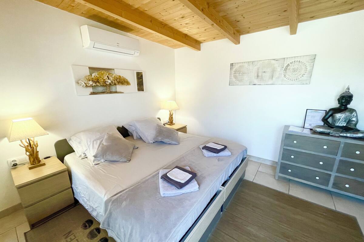 A bedroom with a bed, two bedside tables with lamps, a dresser, and a Buddha statue.