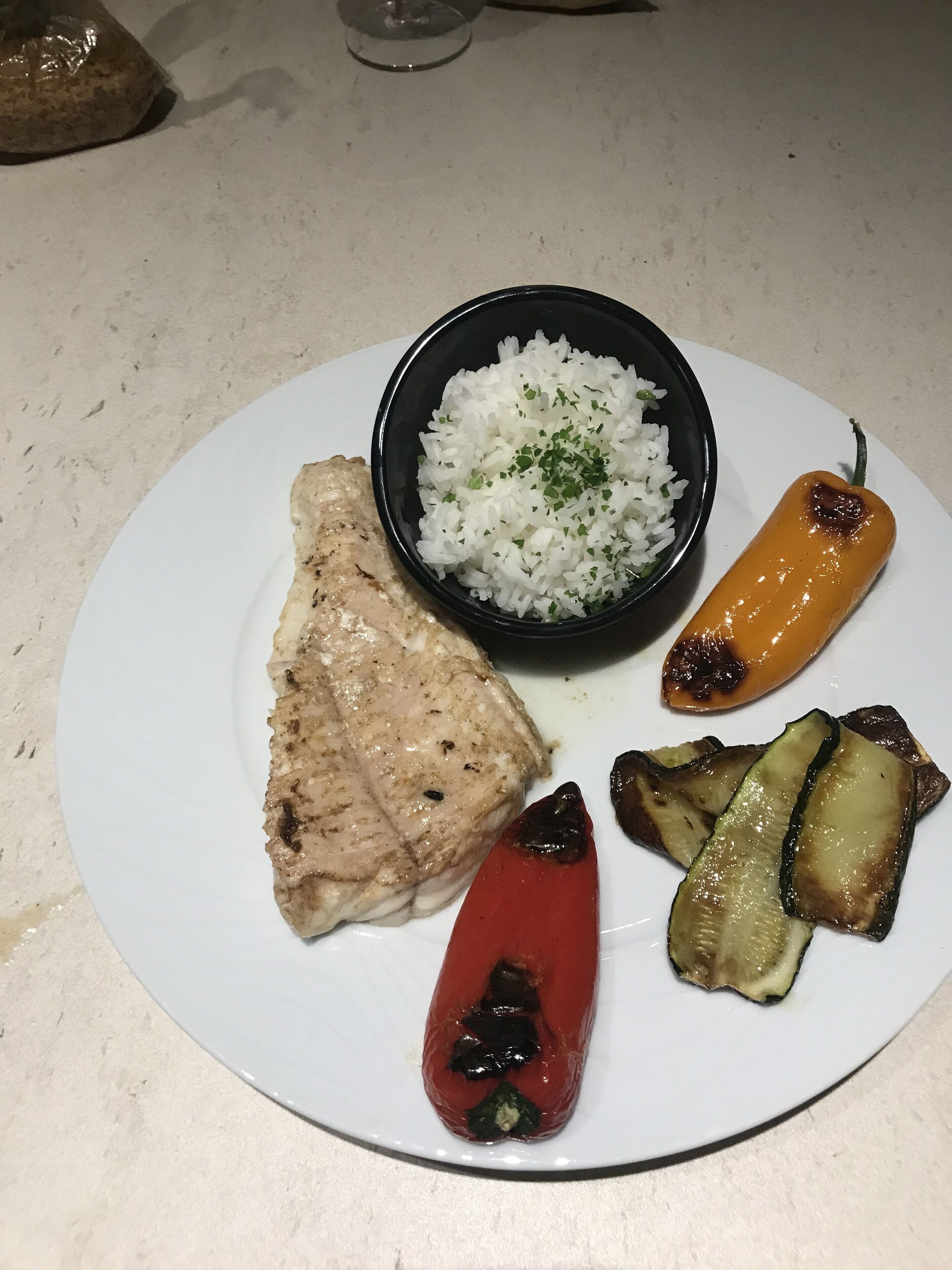Ein Teller mit gegrilltem Hähnchen, weißem Reis, gegrillter Aubergine und einem gegrillten roten Paprika.