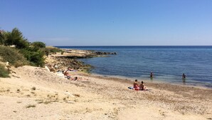 A beach with people sunbathing and swimming, rocky shoreline, and clear blue sky. - B&B L'Escale Cote Bleue (Sausset-les-Pins)
