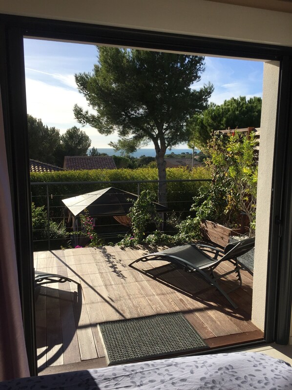 Un patio con terraza de madera, una silla de metal y una mesa.