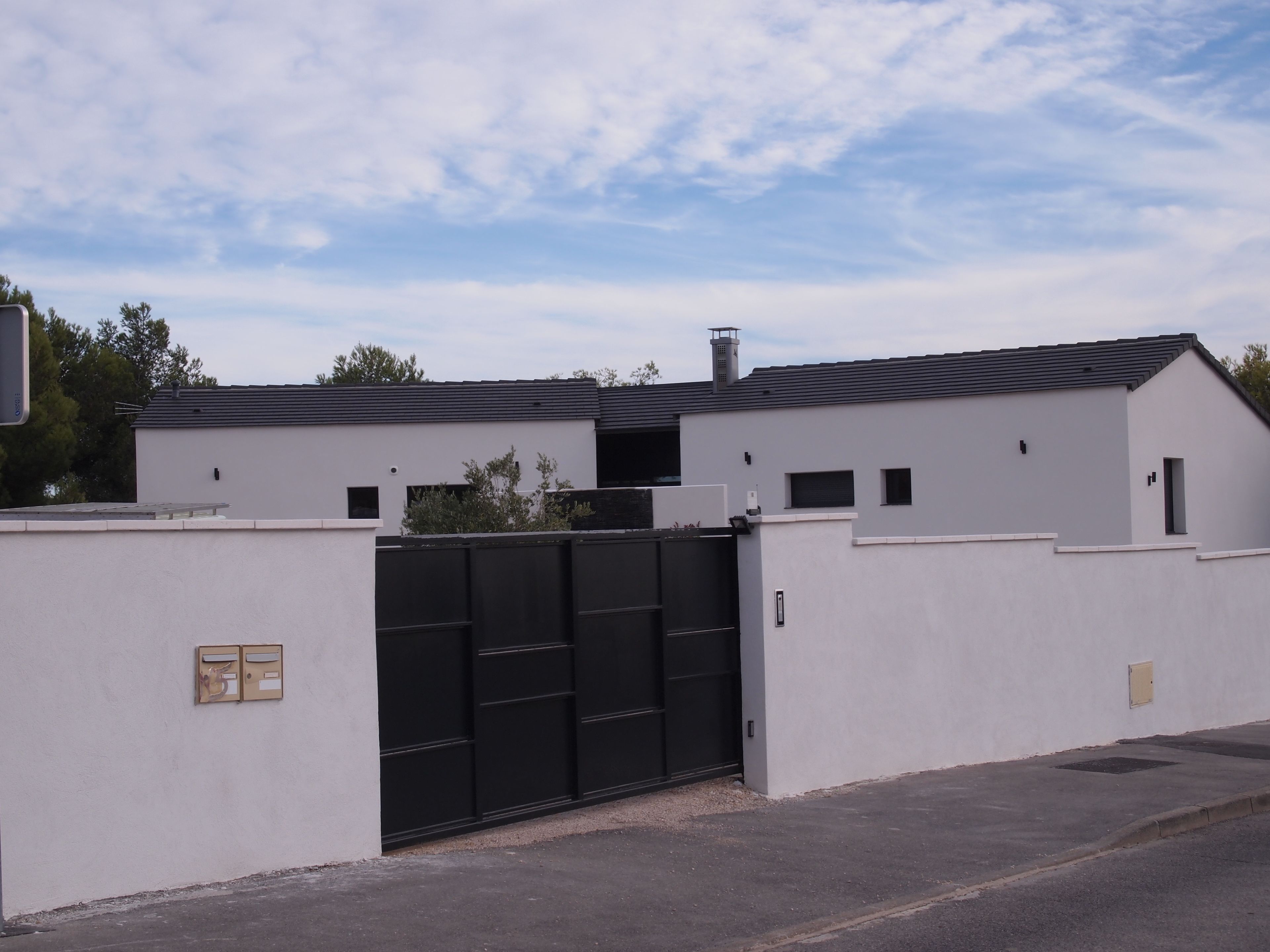 Un bâtiment moderne doté d’un portail noir, de murs blancs et d’un toit en pente.