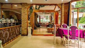 A spacious room with a brick wall, a wooden partition, and a seating area with a sofa and chairs. - Hotel Mountain Top (Manali)