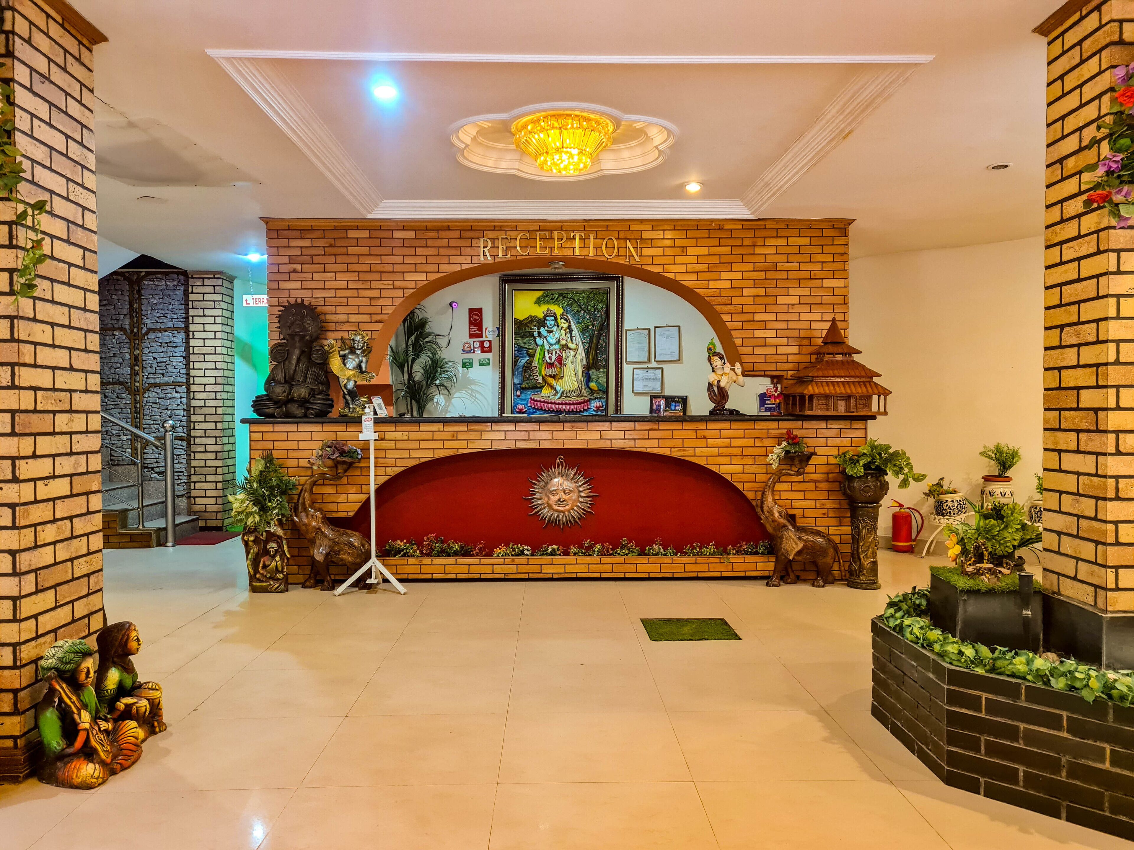A reception area with a brick wall, a chandelier, and a red decorative panel.