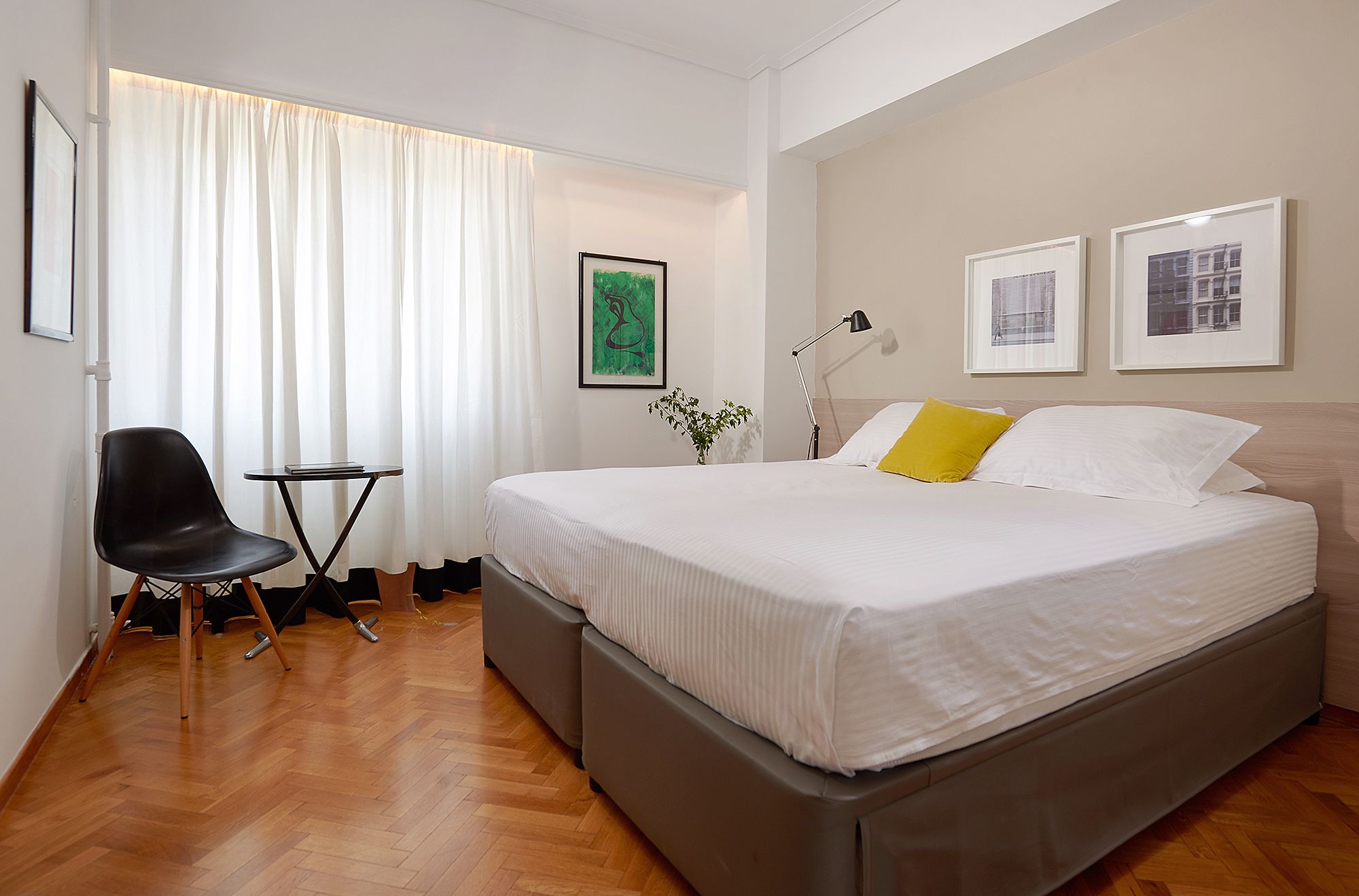 A hotel room with a bed, a chair, a small table, and a lamp.