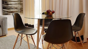 A modern dining area with a glass table, black chairs, and a wooden floor. - Parthenon Apartment (Athens)