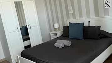 Un dormitorio con cama, mesita de noche, lámpara, armario y pared a rayas.