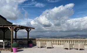 An outdoor seating area with chairs and tables, a pergola, and a view of distant mountains.