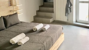 A bedroom with a bed, a wooden headboard, a staircase, and a window with curtains.