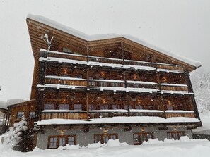 A multi-story wooden building with balconies covered in snow, surrounded by snow. - Residence Valpiccola (Val di Zoldo)