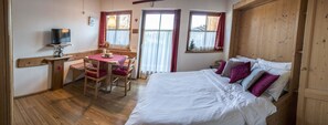 A bedroom with a bed, a desk with a chair, and a television on a shelf. - Residence Valpiccola (Val di Zoldo)