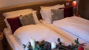 Una cama doble con ropa blanca, un cabecero de madera y una mesita de noche con lámpara.