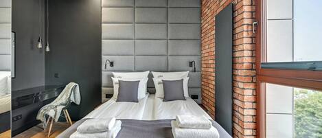 A modern hotel room with a large bed, two bedside tables, a shower, and a view of the outdoors.