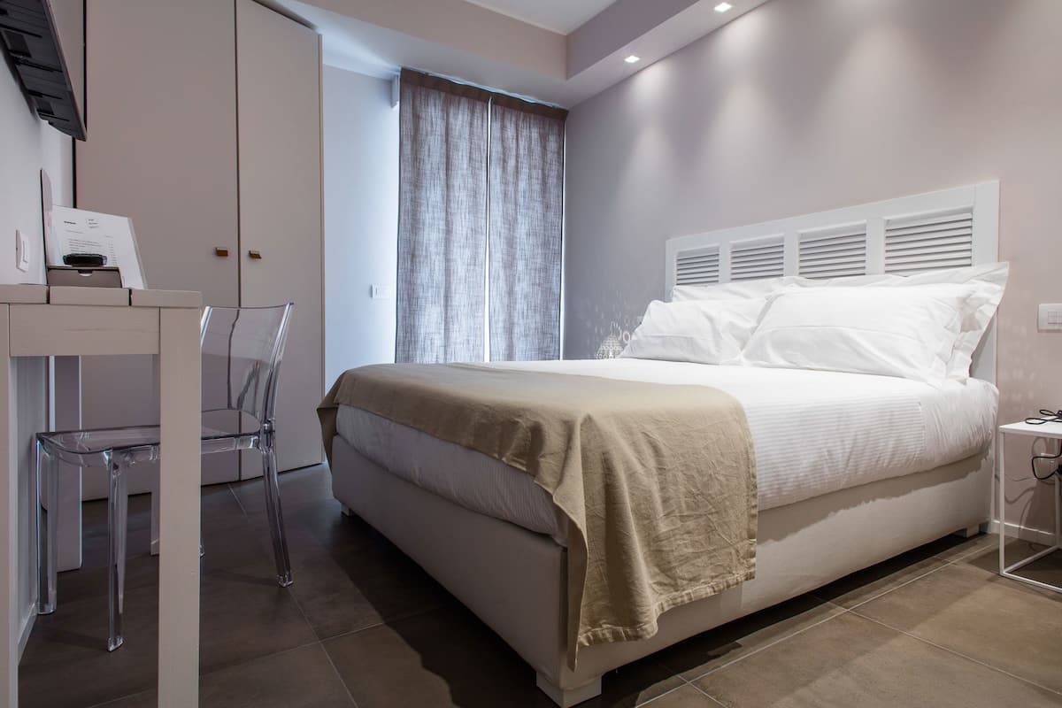 A bedroom with a bed, a desk, and a chair.