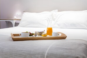 A breakfast tray with coffee, fruit, and orange juice on a bed with white linens. - Mane Boutique Hotel (Roseto degli Abruzzi)