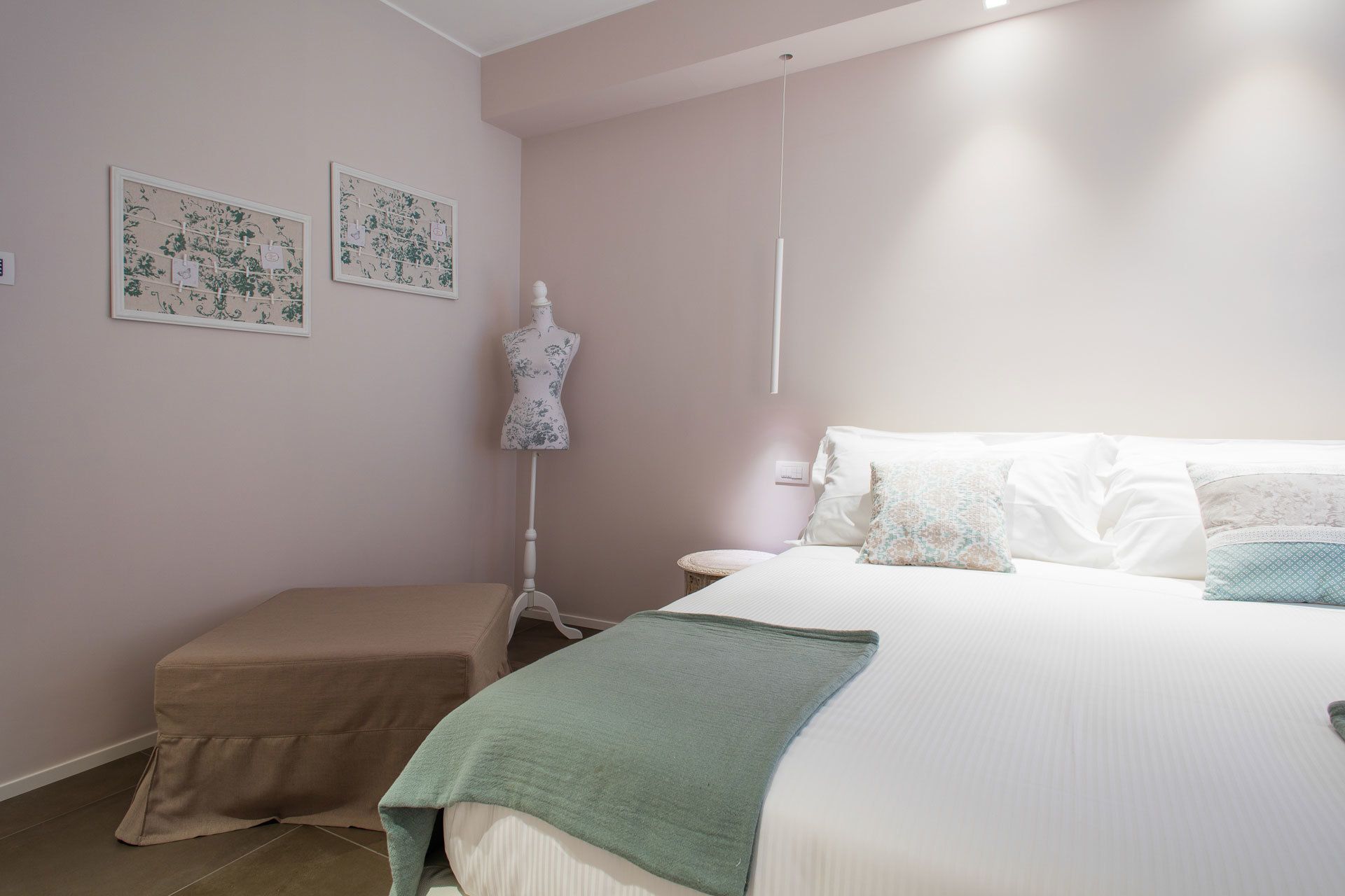 A bedroom with a bed, a bench, and two wall-mounted artworks.