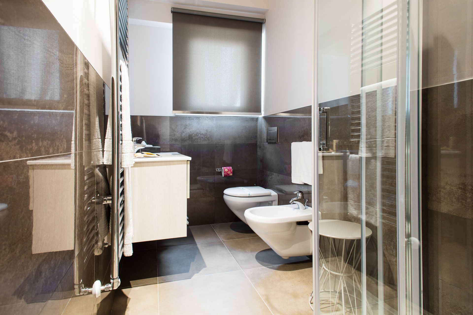 A modern bathroom with a toilet, bidet, and glass shower enclosure.