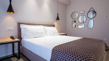 Un dormitorio moderno con una cama, dos mesitas de noche, un espejo en la pared y un enchufe.