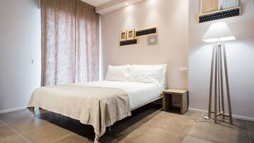 Un dormitorio con cama, mesitas de noche, una lámpara de pie y decoración en la pared.