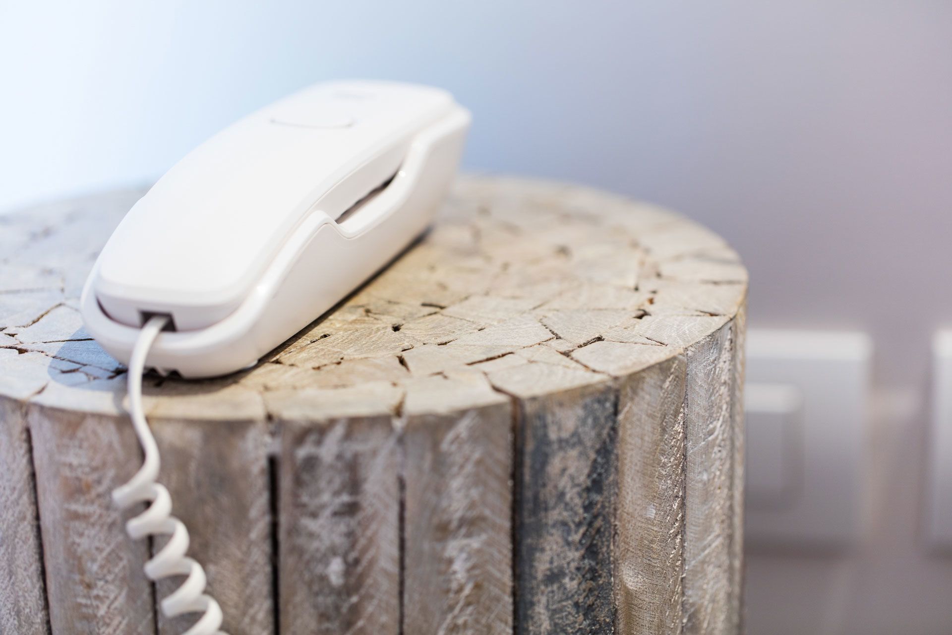 Een witte telefoon op een houten stronk.