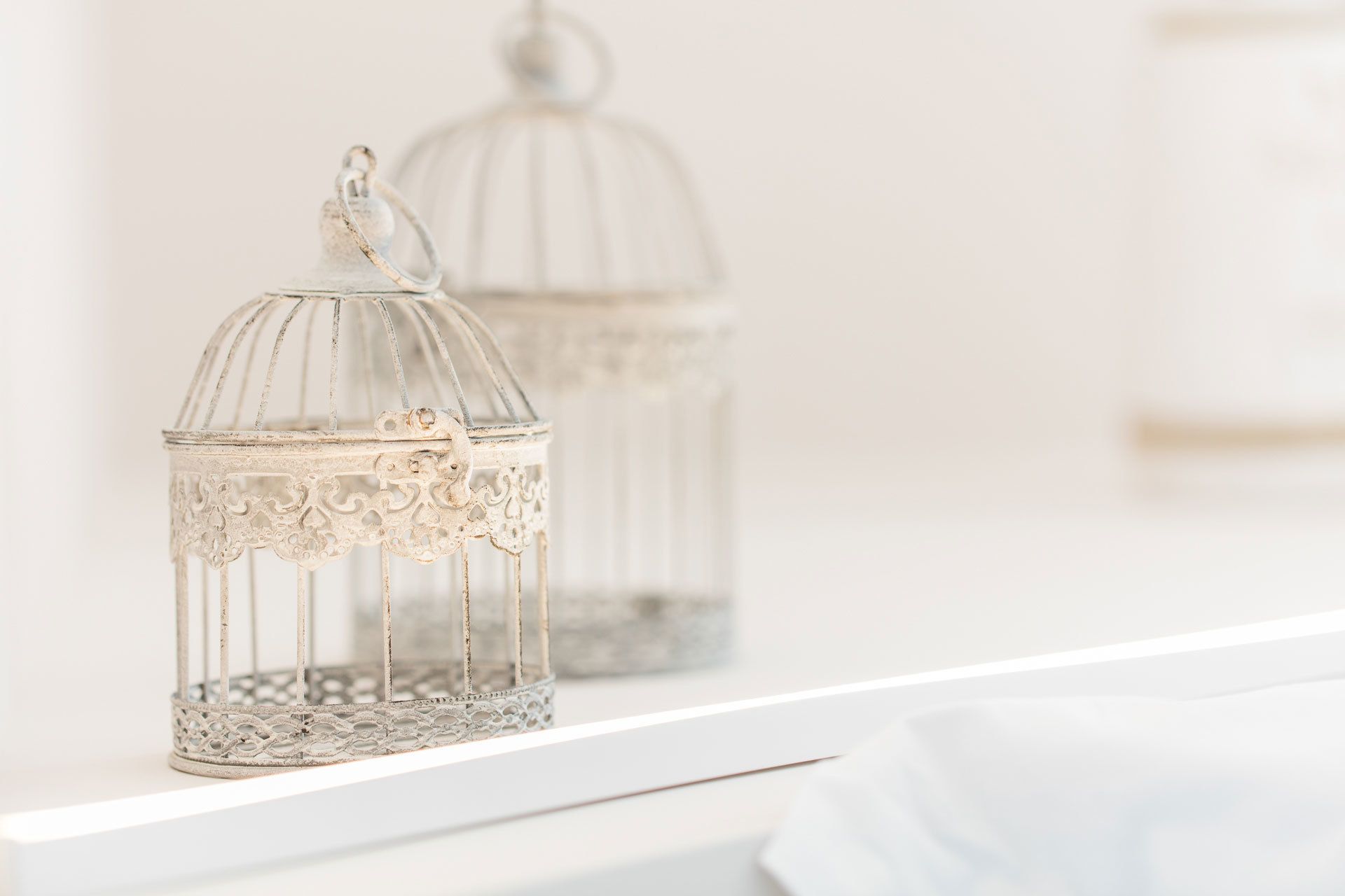 Two ornate glass lanterns with intricate designs, placed on a white surface.