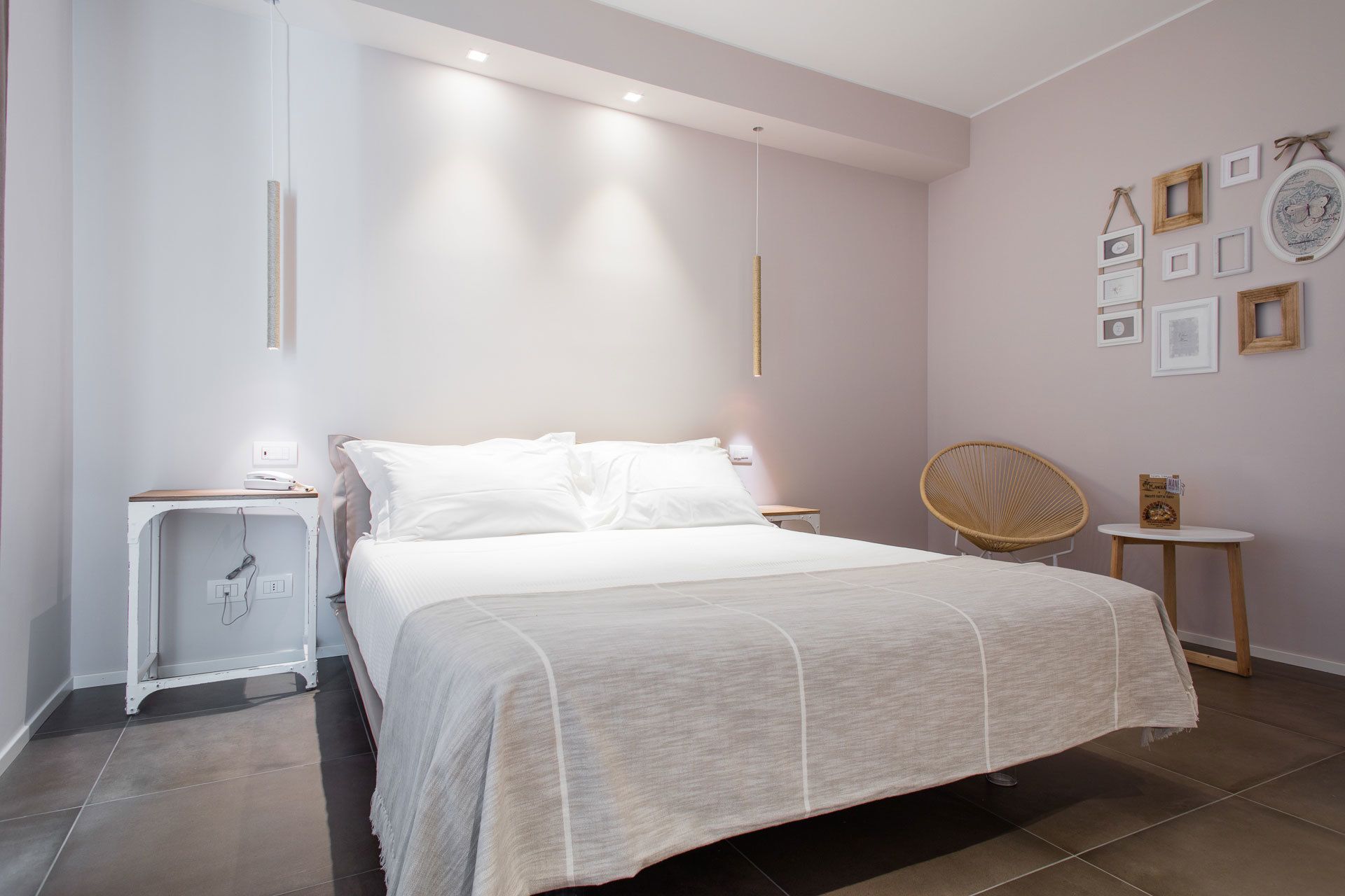 Une chambre moderne avec un grand lit, des tables de chevet, une chaise et des cadres photos accrochés au mur.