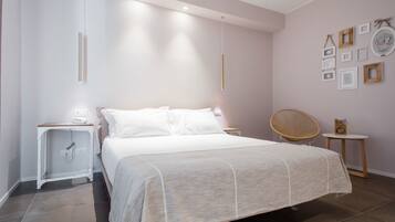 Une chambre moderne avec un grand lit, des tables de chevet, une chaise et des cadres photos accrochés au mur.