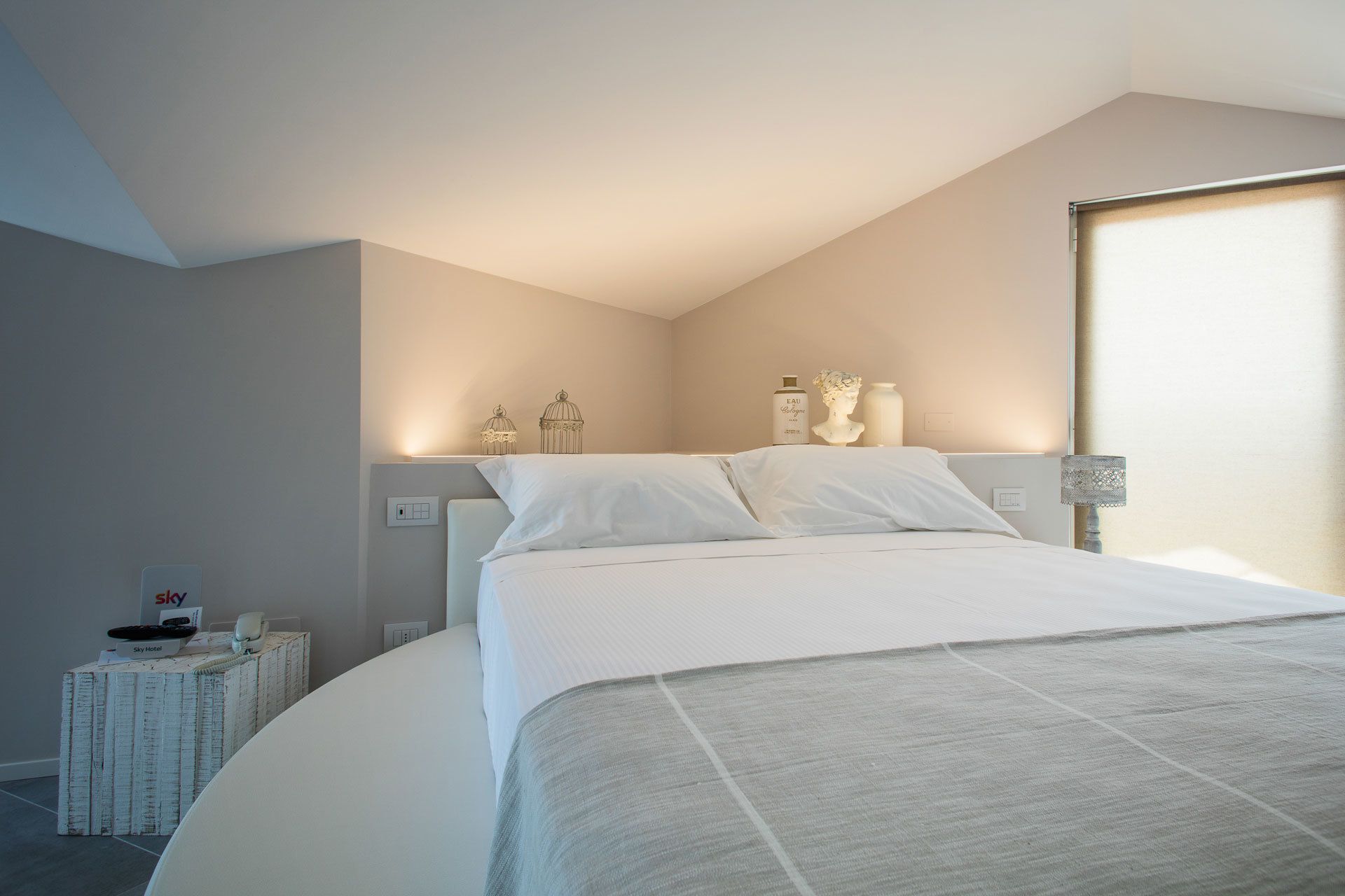 Un dormitorio con una cama grande, una mesita de noche con lámpara y adornos en la pared.
