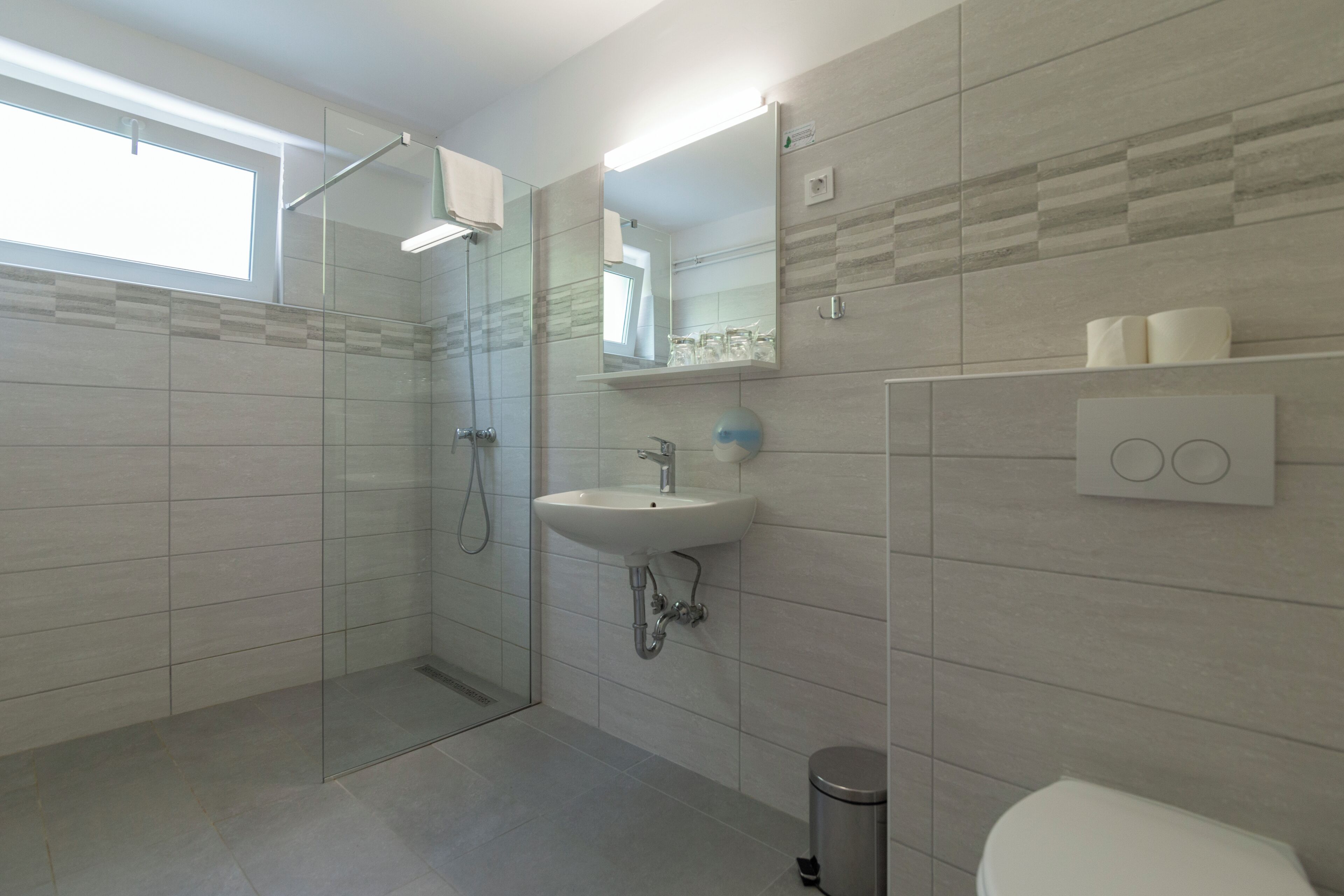 Un baño moderno con cabina de ducha de vidrio, un lavamanos y un inodoro.