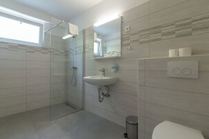 Un baño moderno con cabina de ducha de vidrio, un lavamanos y un inodoro.
