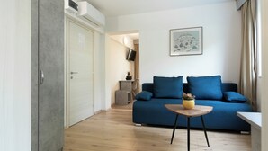 A modern living room with a blue sofa, a small wooden table, and a grey wardrobe. - Boarding House Lucija (Kostrena)