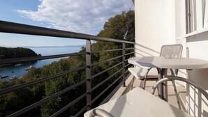A balcony with a table and chairs overlooking a bay with boats and greenery. - Boarding House Lucija (Kostrena)