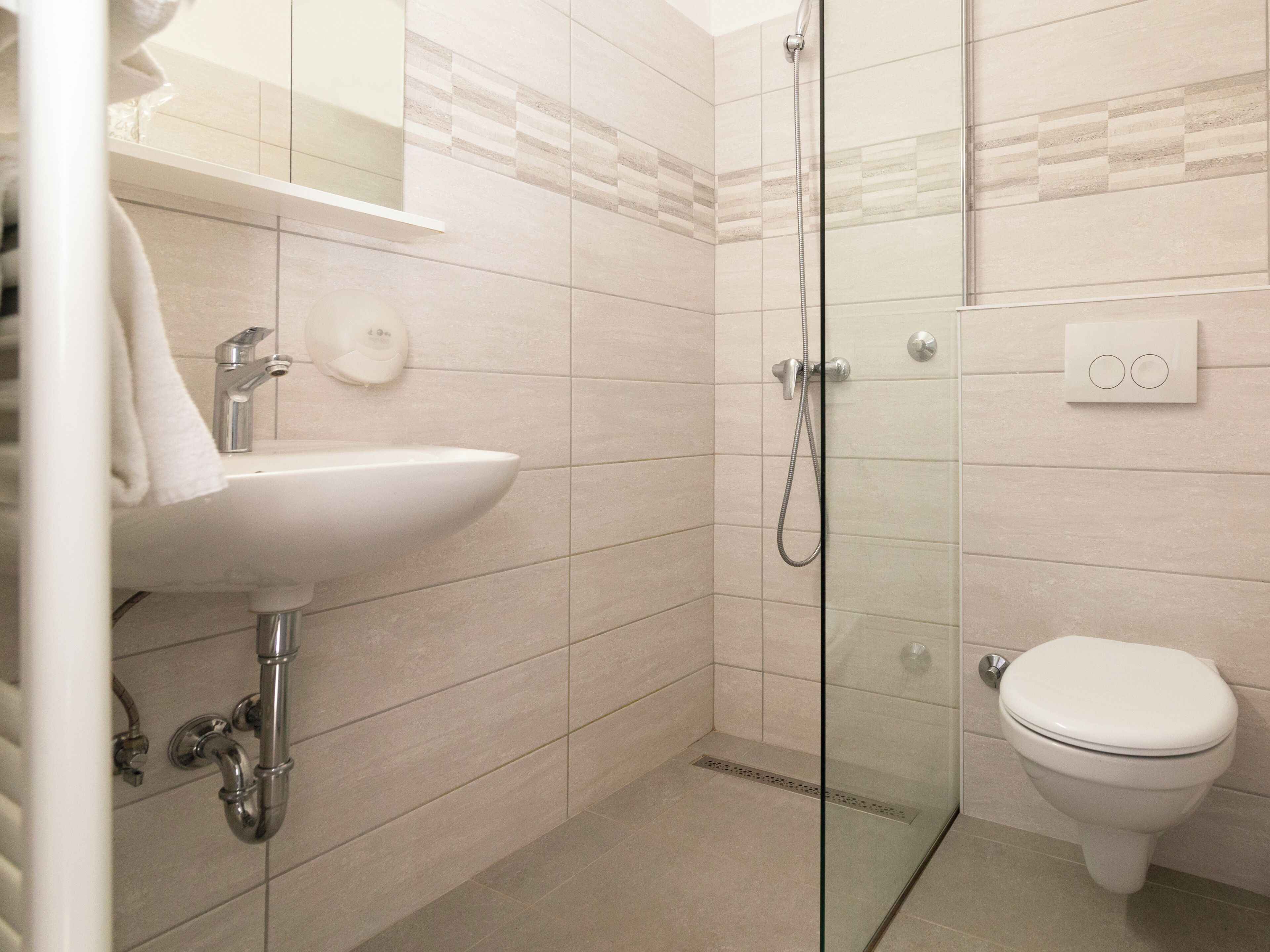Une salle de bain moderne avec une douche à parois de verre, un lavabo blanc et des toilettes.