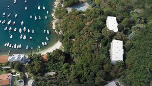 An aerial view of a coastal area with numerous boats docked at a marina, surrounded by dense greenery and residential buildings. - Boarding House Lucija (Kostrena)