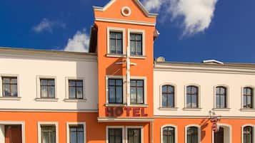 A hotel with a prominent orange facade, multiple windows, and a clear blue sky in the background.