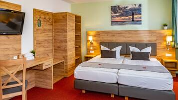 A hotel room with a large bed, a desk, a TV, and a painting on the wall.