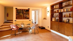 A spacious living area with a sofa, two chairs, a coffee table, and a bookshelf filled with books and decorative items. - Villetta Capodimonte Guest House (Naples)